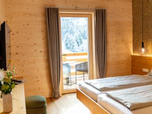 a bedroom with a bed and a large window at Berghotel Wald&Wiesn in Balderschwang