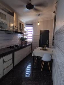 a kitchen with a table and a white table and chairs at Chegebu Homestay in Kampong Beringin