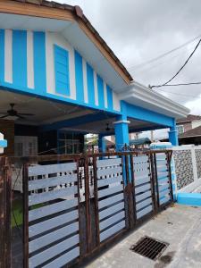 a blue and white house with a gate at Chegebu Homestay in Kampong Beringin