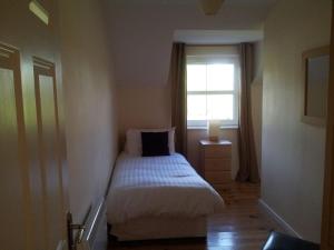 um pequeno quarto com uma cama e uma janela em 15 Sheen View Kenmare Co Kerry em Kenmare