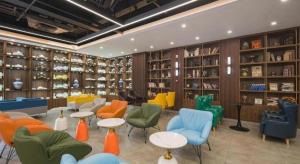 eine Bibliothek mit bunten Stühlen, Tischen und Bücherregalen in der Unterkunft James Joyce Coffetel Tianjin Railway Station Jinshiqiao Metro Station Branch in Tianjin