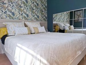 FollignyLe petit logis的卧室配有一张白色大床和花卉壁纸