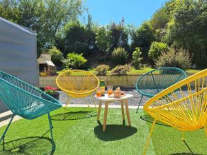 three chairs and a table with food on it in a yard at Le petit logis in Folligny
