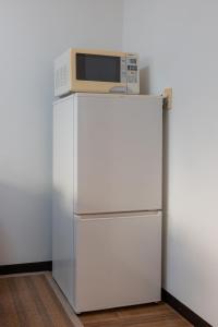 Un microondas encima de un refrigerador blanco. en Guesthouse & Kitchen Hace - Vacation STAY 68911v, en Iwaki