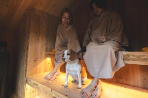 a man and a woman in a sauna with a dog at Earthboat Nasu - Glamping Cabin with Private Wood-Fired Sauna & Onsen, Pet-Friendly & Cage-Free in Nasu