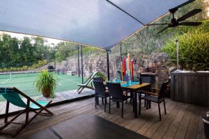 a patio with a table and chairs and a tennis court at Garasu Lodge in Gold Coast