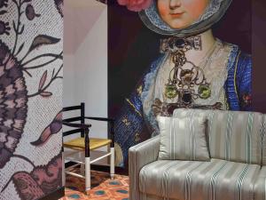 ein Gemälde einer Frauenbüste neben einem Stuhl in der Unterkunft Jules César Hotel & Spa Arles - MGallery Collection in Arles