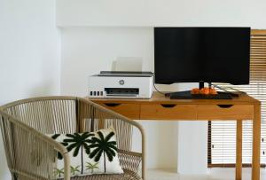 un monitor de ordenador sentado en un escritorio de madera con una silla en Ubud Dzen Villa 3, en Ubud