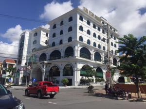 a red truck driving in front of a white building at Hai Yen Luxury Hotel in Cẩm Phả