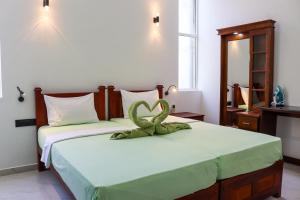 a bedroom with two beds with a green snake on it at The Green Homestay - Galle in Galle