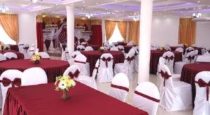 a banquet hall with red and white tables and chairs at Hotel Glee in Challi
