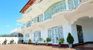 a white building with potted plants in front of it at Hotel Glee in Challi