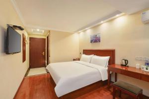 a bedroom with a large white bed and a desk at GreenTree Inn Nanjing Forestry University National Exhibition Center Express Hotel in Nanjing