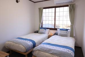 zwei Betten in einem Zimmer mit Fenster in der Unterkunft Forest and Stars Akakura Lodge in Myōkō