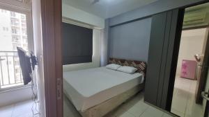 OYO 95052 Cordia Tower في Tjikuda Dua: غرفة نوم صغيرة مع سرير أبيض ونافذة