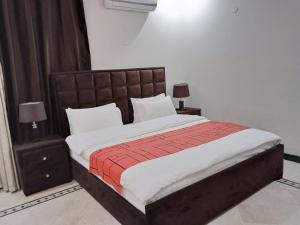 a bedroom with a large bed with white and red sheets at Islamabad Pak Palace guest house in Islamabad