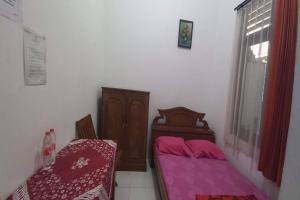 a small bedroom with two beds and a window at OYO 95058 Agago Homestay Syariah in Kedungtengkong