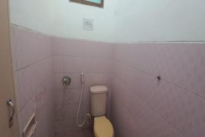 a bathroom with a toilet and pink tile walls at OYO 95058 Agago Homestay Syariah in Kedungtengkong +16 photos