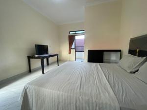 Sultan Syarif Kasim II International AirportCapital O 95046 Gefa Sleep N Go的卧室里有一张白色的床和一张书桌 更多27张照片