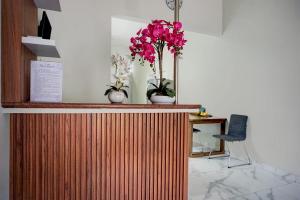 a counter with two vases with pink flowers on it at OYO 95054 Prima Jaya Homestay Syariah in Kedungtengkong