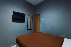 a bedroom with a bed with a flat screen tv on the wall at OYO 95060 Ahzafani Homestay Syariah in Godangrawe +16 photos