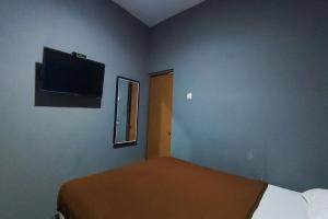 a bedroom with a bed and a flat screen tv at OYO 95060 Ahzafani Homestay Syariah in Godangrawe