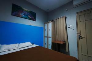 a blue bedroom with a bed and a blue wall at OYO 95060 Ahzafani Homestay Syariah in Godangrawe