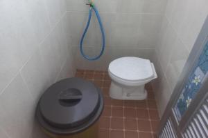 a bathroom with a toilet and a blue hose at Hotel O Guest House Wijaya Syariah Near alun alun kota purwokerto in Purwokerto
