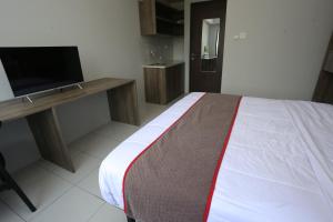 Un dormitorio con una cama y un escritorio con televisión. en Capital O 95049 Aurora Rooms @ Riverdale, en Tanahbaru 18 fotos más