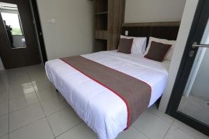 1 dormitorio con 1 cama grande con sábanas blancas y almohadas rojas en Capital O 95049 Aurora Rooms @ Riverdale, en Tanahbaru
