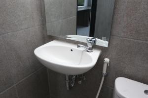 Un lavabo blanco en un baño con espejo. en Capital O 95049 Aurora Rooms @ Riverdale, en Tanahbaru