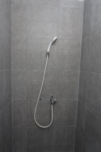y baño con ducha con manguera blanca. en Capital O 95049 Aurora Rooms @ Riverdale, en Tanahbaru