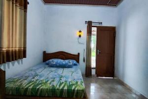 a bedroom with a bed with a blue pillow on it at OYO 95055 Homestay Panasan Pak Budi in Kedungtengkong