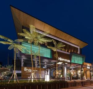a building with palm trees in front of it at Hinn - Namm Hotel in Hua Hin