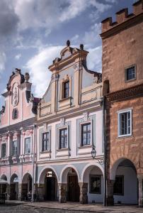 a large building with a tower next to a brick building at Apartmany Chornitzeruv dum in Telč