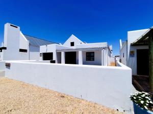 a white house with a white wall at Mosseltjie - Self Catering in Britannia Bay