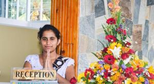 a woman sitting at a podium with her index finger up at Lion Nature in Weliara