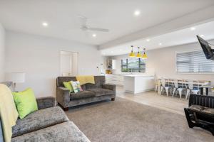 a living room with two couches and a kitchen at Peaceful Paradise - Waihi Beach Holiday Home in Waihi Beach
