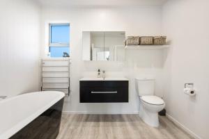 a white bathroom with a toilet and a sink at Peaceful Paradise - Waihi Beach Holiday Home in Waihi Beach +19 photos