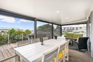 a white table with a bottle of wine on a balcony at Peaceful Paradise - Waihi Beach Holiday Home in Waihi Beach