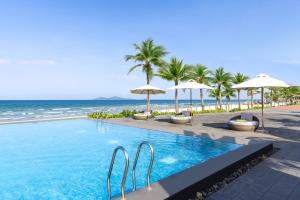 a swimming pool next to the beach with umbrellas at Melia Danang Beach Resort in Da Nang