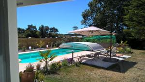 a swimming pool with an umbrella and a table and chairs at Kerzara - Le Gîte in Sarzeau