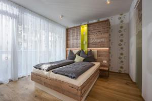 1 dormitorio con 1 cama con pared de madera en Private Living Apartments, en Kufstein