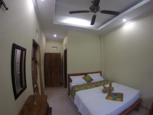 a bedroom with a bed and a ceiling fan at Utari House in Ubud