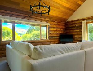 ein Wohnzimmer mit einem weißen Sofa und einem Fernseher in der Unterkunft Large Ski Club Style Lodge, Views, Walk to town in Wanaka