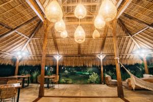 een grote kamer met tafels en stoelen en kroonluchters bij Green Escape Eco Resort in Uluwatu