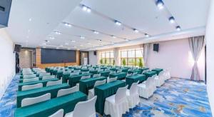 una sala conferenze con sedie verdi e bianche e uno schermo di Jinjiang Inn select Hotel Kunming Economic Development Zone Kunming College a Kunming