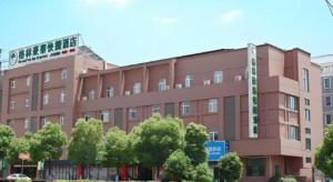 un grande edificio marrone con alberi di fronte di GreenTree Inn Nanjing Lishui District Lishui Airport Road Express Hotel a Lishui