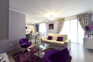 sala de estar con sofá blanco y sillas moradas en Djanea Luxury Apartment - Disneyland Paris, en Serris