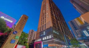 ein hohes Gebäude mitten in einer Stadt in der Unterkunft Lavande Hotel Wuhan East Lake Xudong Metro Station in Wuhan